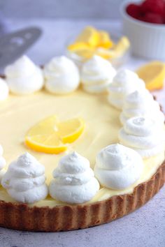 a lemon tart topped with whipped cream and sliced lemons on a white table