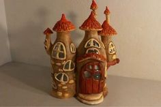 two clay houses sitting on top of a white table next to each other with red roof tops