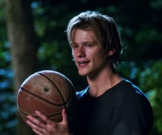 a young man holding a basketball in his hands