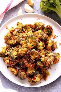 broccoli florets on a white plate next to garlic