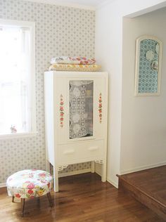 a white cabinet sitting in the corner of a living room next to a wooden floor