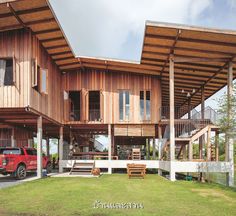 a red truck parked in front of a large wooden building with balconies on the roof