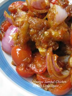 a blue and white plate topped with onions, tomatoes and other foodstuffs covered in sauce