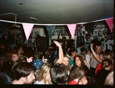 a group of people standing around each other in a room with pink and blue flags