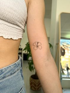 a woman's left arm with a small flower tattoo on the right side of her body