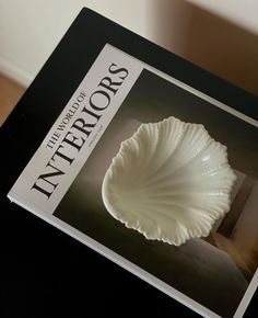 a book with an image of a white shell on it's cover is sitting on a table