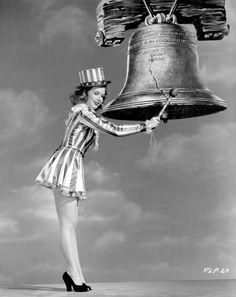 a woman in a striped dress is holding a large bell