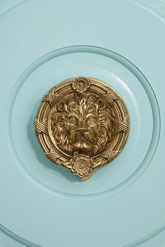 a gold lion head on a light blue plate