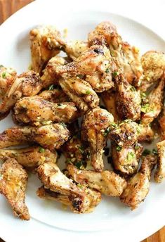 a white plate topped with chicken wings on top of a wooden table