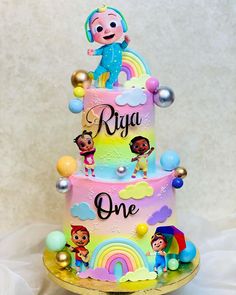 a three tiered cake decorated with cartoon characters and rainbows on the bottom layer