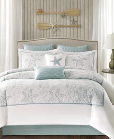 a bed with white and blue comforters in front of a wooden paneled wall