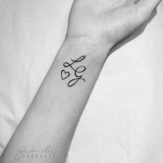 a black and white photo of a person's wrist with the word love tattooed on it