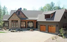 a large house with two garages in front of it and lots of trees around