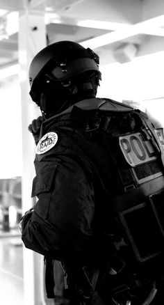 a police officer standing in an airport with his back to the camera and looking at something