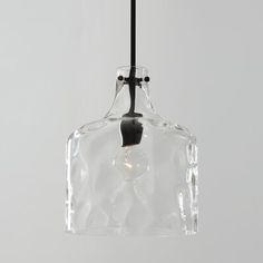 a clear glass light hanging from a black metal hook on a gray wall with a white background