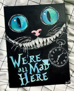 there is a black cat with blue eyes on it's face and the words we're all mad here