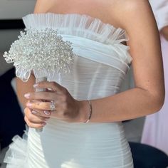 a close up of a person wearing a wedding dress and holding a ring on her finger