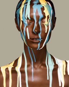 a woman with blue and yellow paint on her face, painted in white and brown