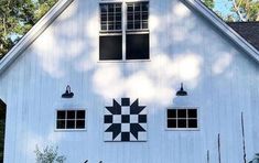 a large white barn with a black and white quilt on the front window sill