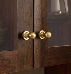 two brass knobs on the side of a wooden cabinet