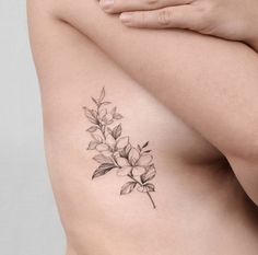 a woman's stomach with a flower tattoo on her left side ribcage