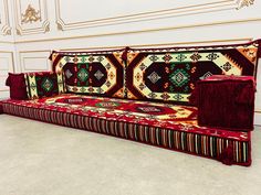 a couch made out of rugs in a room with white walls and flooring