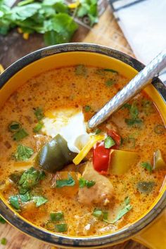 a close up of a bowl of soup on a wooden table with a spoon in it