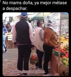 two people standing next to each other in front of a fruit stand