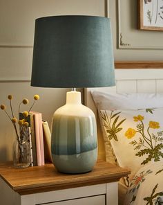 a lamp sitting on top of a wooden table next to a night stand with books