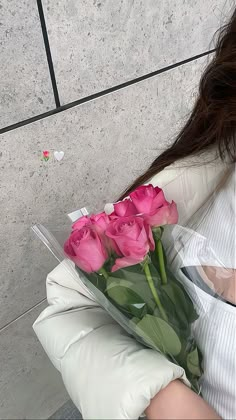 a woman holding a bouquet of pink roses