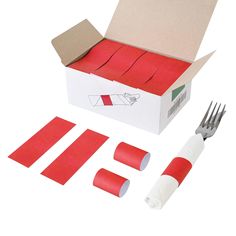 a box with red tape, fork and knife in it next to some pieces of paper