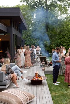 a group of people gathered around a fire pit on a deck with couches and chairs