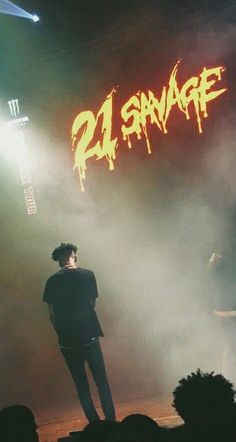 a man standing on top of a stage under a neon sign that reads 21 strange