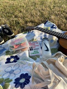 an ukulele and other items are laid out on a blanket in the grass