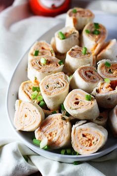 a white plate topped with rolls covered in meat and veggies next to a bottle of ketchup