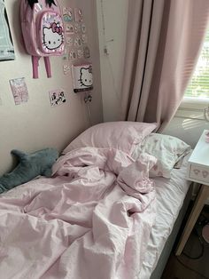 a bed with pink sheets and hello kitty decorations on the wall