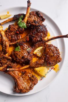 a white plate topped with lamb chops and pineapple wedges on top of a table