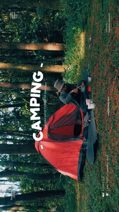 a man laying on the ground next to a red tent with camping written over it