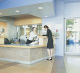 two women are standing at the front desk of a hotel reception area and one woman is paying for her ticket