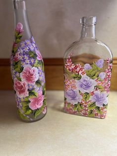 two glass bottles with flowers painted on them