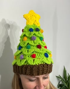 a woman wearing a crocheted christmas tree hat