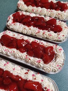 four desserts with white frosting and strawberries on them are arranged in rows