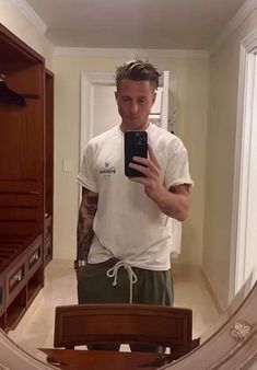 a man standing in front of a mirror holding a cell phone and taking a selfie