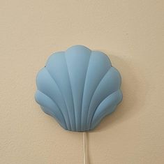 a light blue scallop hanging on the wall next to a white painted wall