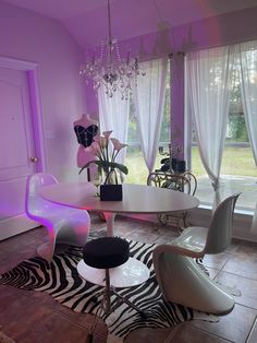 a dining room with purple lighting and zebra print rugs on the floor in front of large windows