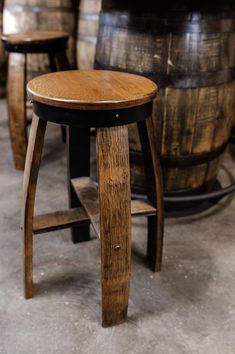 two wooden stools sitting next to each other in front of some wine casks