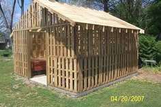 a building made out of wooden slats in the grass with trees in the background