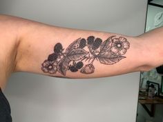 a woman's arm with flowers and leaves tattooed on the left side of her arm