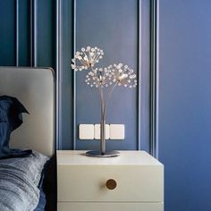 a white bed sitting next to a night stand with a flower on top of it