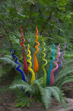 a group of multicolored glass sculptures sitting on top of a tree stump in the woods